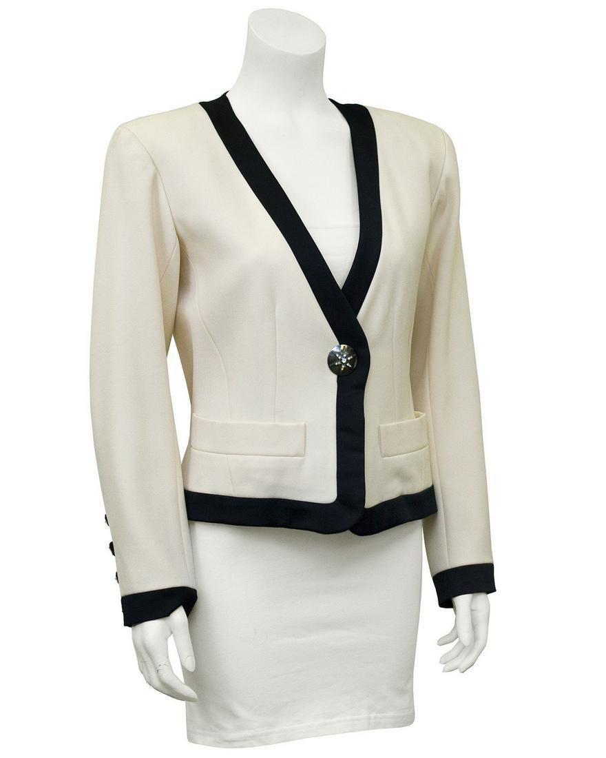 Yves Saint Laurent Cream Cropped Jacket with Black: Great 1980's Yves Saint Laurent cropped cream wool gabardine jacket with thick black satin trim. One stunning large sliver button at center embellished with rhinestone star symbol. Five smaller matchi