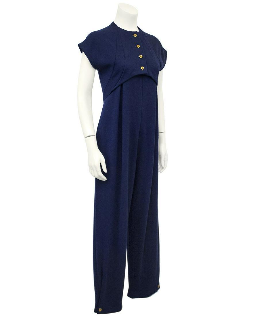 Geoffery Beene Navy Wool Jersey Jumpsuit: Cap sleeved Geoffrey Beene navy wool jersey blend jumpsuit from the 1980s. The overlaying top has gold buttons down the front and appears like a cropped bolero with curved seams down the sides and hit