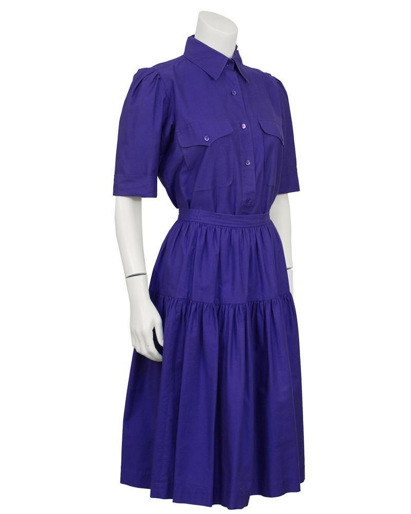 Yves Saint Laurent Purple Cotton Skirt Ensemble: Purple cotton YSL skirt and button down ensemble from the 1970's. Collared shirt with small purple buttons down the front, top flap pockets on the bust and short sleeves. Yoke on the back, sleeves can
