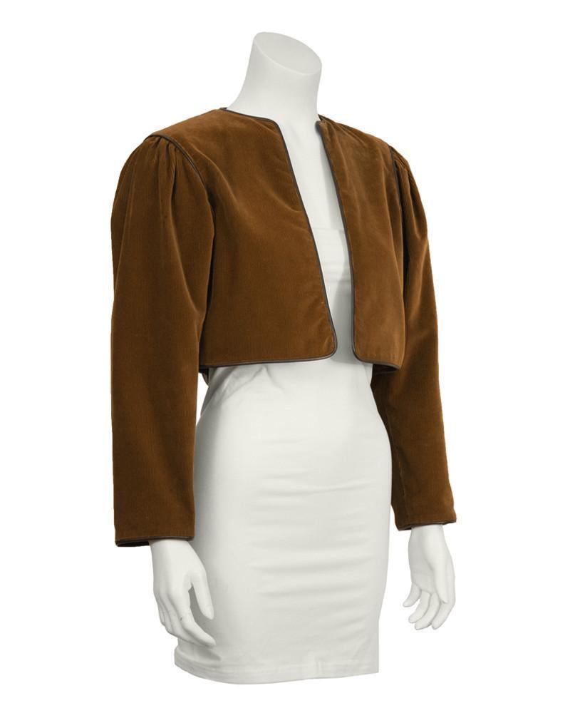 Yves Saint Laurent Brown Corduroy Bolero Jacket: 1970's iconic Yves Saint Laurent cropped brown corduroy bolero jacket with dark brown leather piping. Slight gathering at shoulder and lined in brown satin. In excellent condition. Fits like a US size