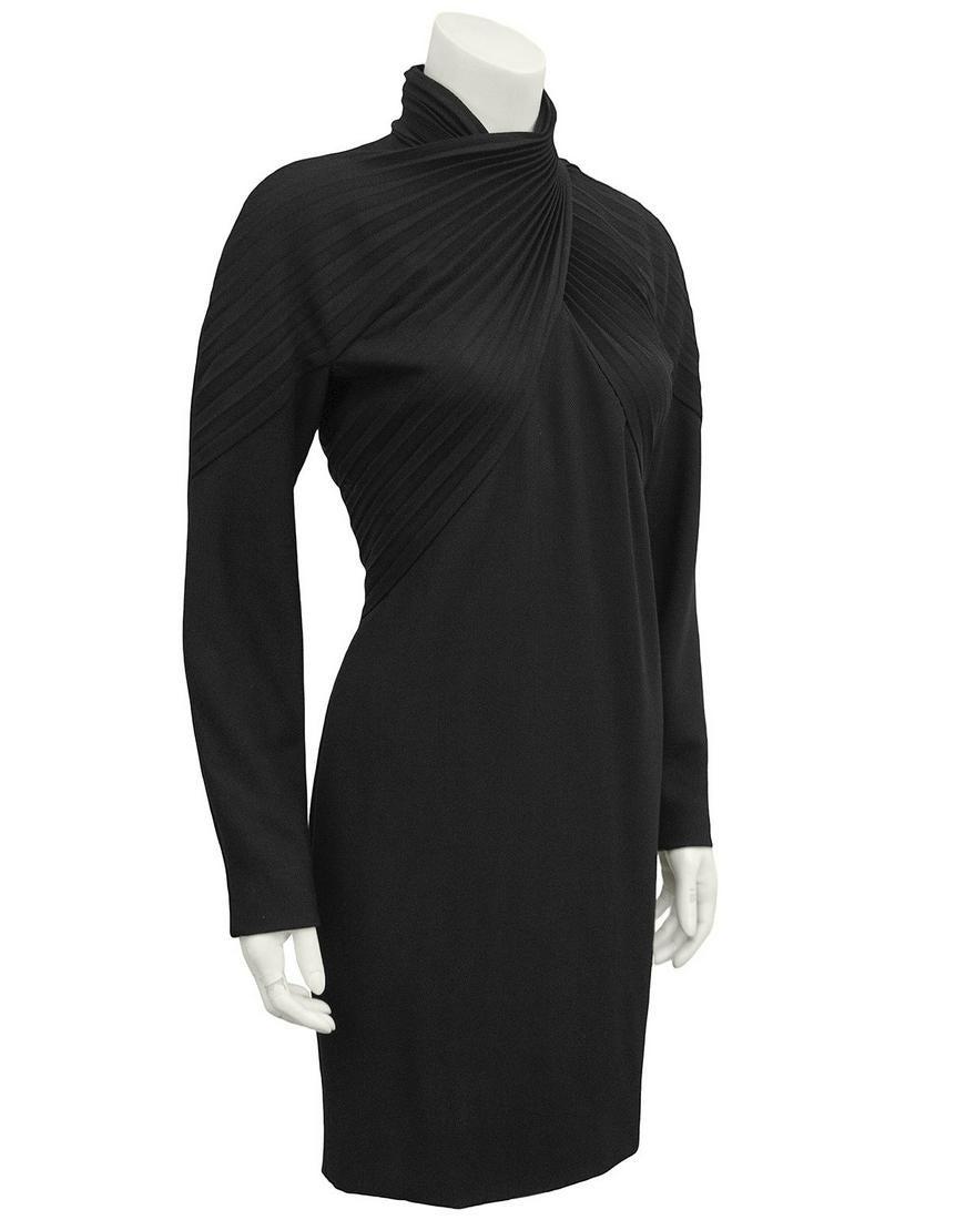 Versace Black Wool Cocktail Dress: 1980s black label Gianni Versace black wool cocktail dress featuring long sleeves and a turtle neckline. Beautiful pleating details at the bust that cross and wrap around the neck, creating a turtlene