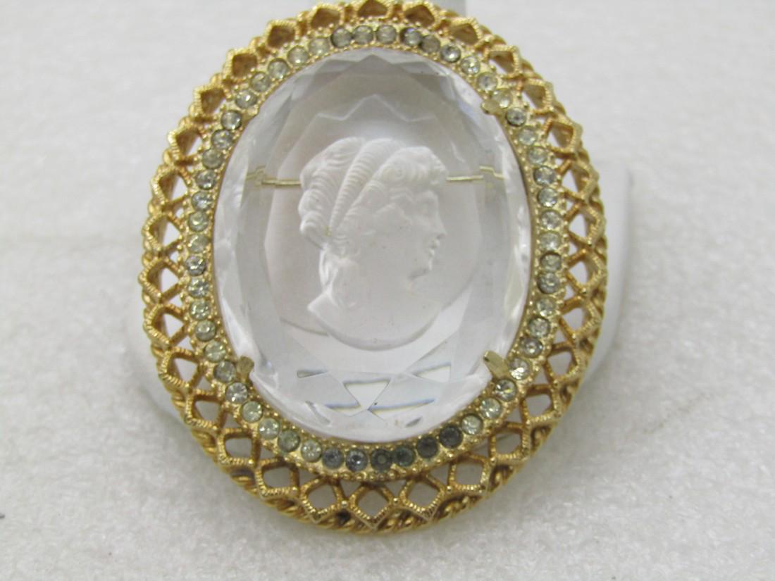 Vintage Clear Reverse Cut Cameo, Intaglio, 1960's, Gold: Vintage Clear Reverse Cut Cameo, Intaglio, 1960's, Gold Tone, 2.25" tall and appx. 1.5" wide.ÿ Gold tone open frame with a rhinestone halo around the stone.ÿ There are six darkened stones at the bot