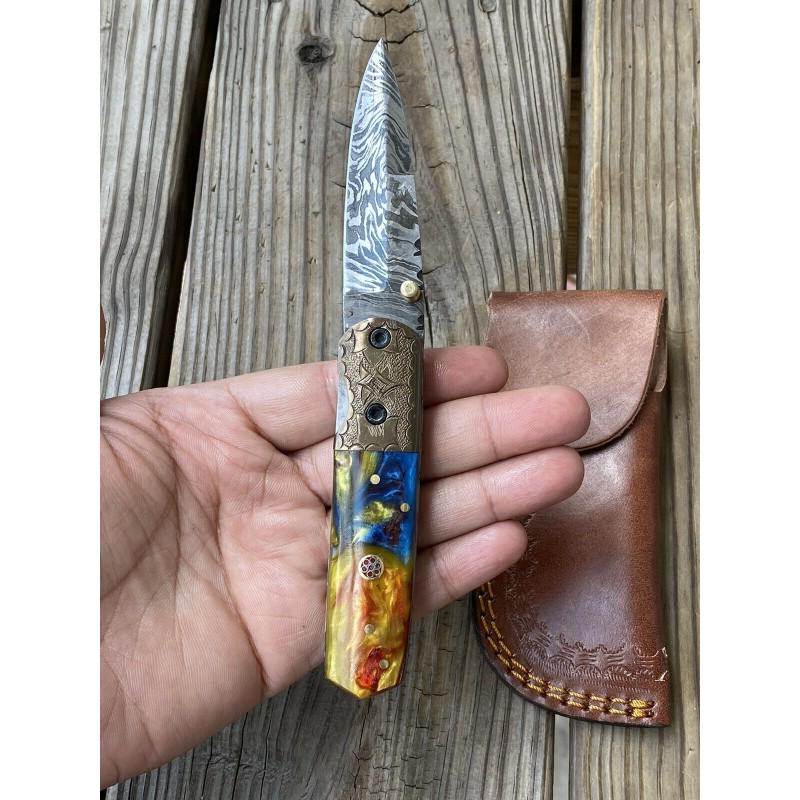 Damascus steel knife, resin and engraved bolster: Knife "Adventure" made of damask steel. Handle – resin and engraved bolster and scabbard – leather. Damascus knives are very durable, look great and keep sharpness perfectly. Damascus steel has hi