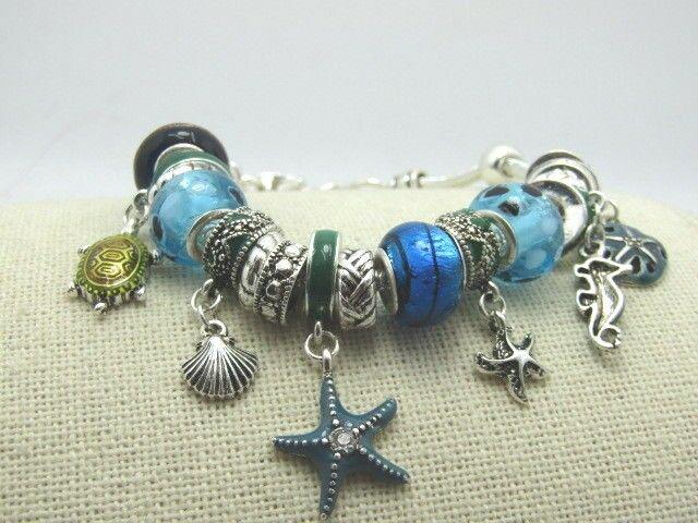Glass & Enamel Beaded Charm Bracelet, 8.25", Blue,: Glass & Enamel Blue Beaded Charm Bracelet - Sea and Ocean themed with charms that include: sand dollar, two starfish, shell, turtle - 4 are enameled. There are four glass beads that have silver tone i