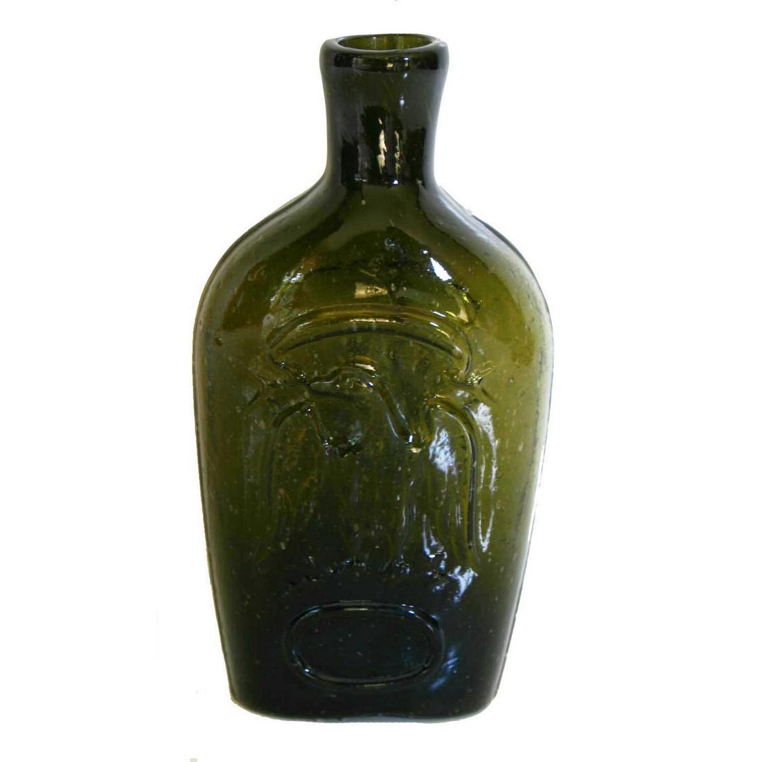 Blown Molded Eagle Flask: Title: Blown Molded Eagle Flask Provenance/Additional Info: This early blown-molded flask is in olive-green colored glass. It has a ribbon over a spread-winged eagle with a central shield over an oval