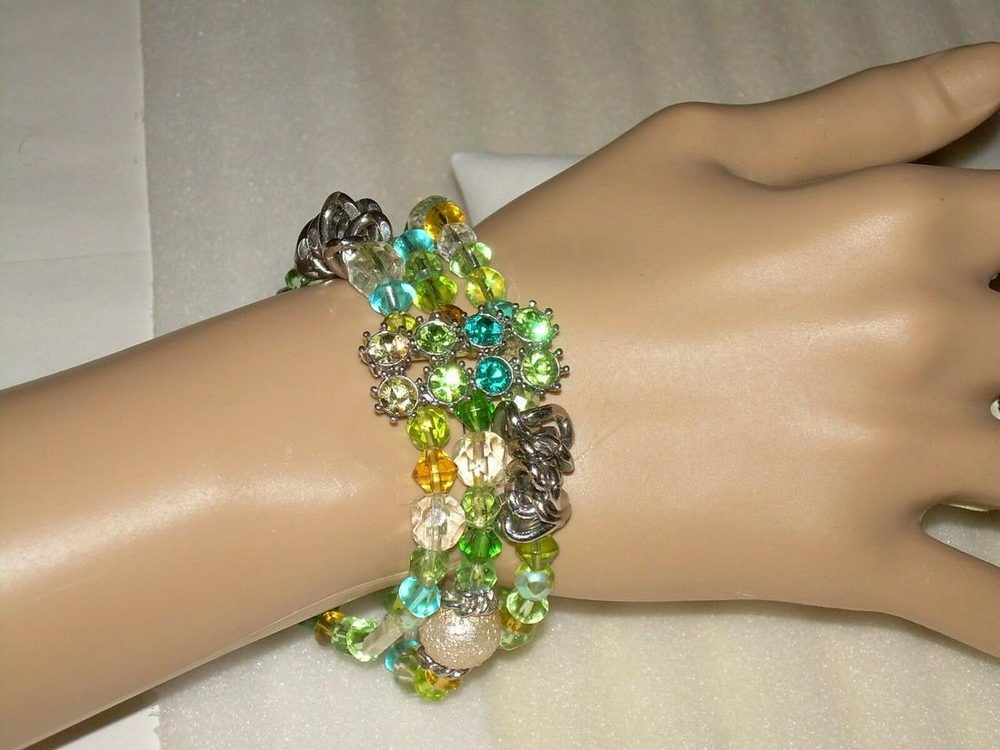 Multi Strand Glass Beaded Bracelet With Rhinestone: Vintage multi strand glass beaded bracelet. The bracelet comes with green, blue, clear, amber glass beads . There are silver tone accent swirl links and spacers. There is a double row of rhinestones w