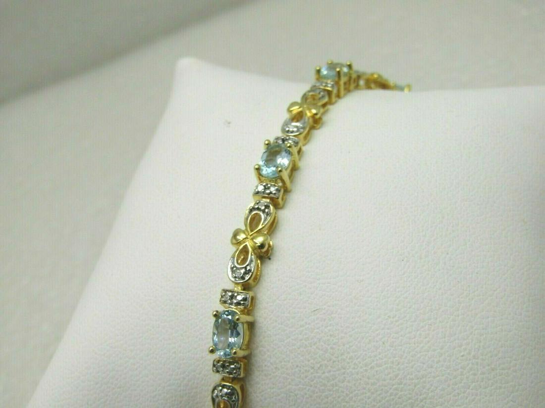 Sterling Gold Over Topaz Tennis Bracelet, 7.75",: Sterling Silver Goldwashed Blue Topaz Tennis Bracelet, illusion setting, there is a single diamond chip in one of the bow-like links that connect each topaz link and the rest of the diamond look is an