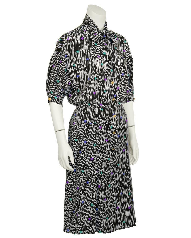 Versace Black Printed Silk Day Dress: Early 1990's Versace ladies-who-lunch silk day dress made with an allover black and white zebra-like pattern with accents of blue, purple, and green. Features a pussy cat tie bow at the neck, gold but