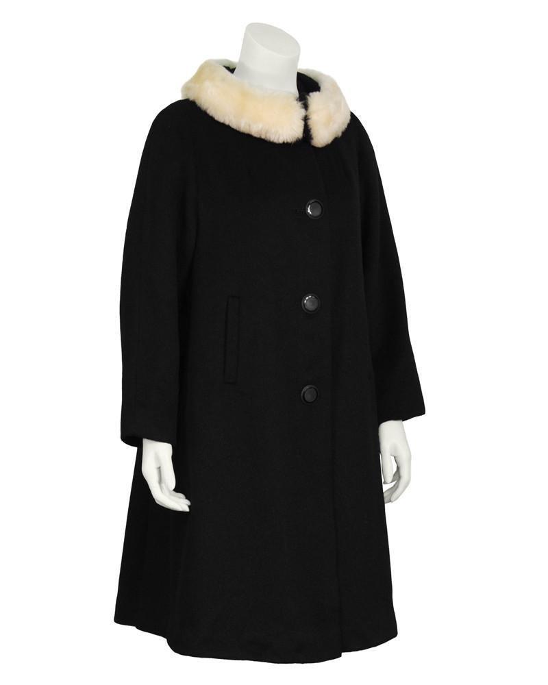 Lilli Ann Black Wool Swing Coat: Lilli Ann 1960’s black wool swing coat with a cream faux fur detail at neck. The coat does up the front with large black circular buttons and the faux fur collar closes with large hook and eyes. Fea
