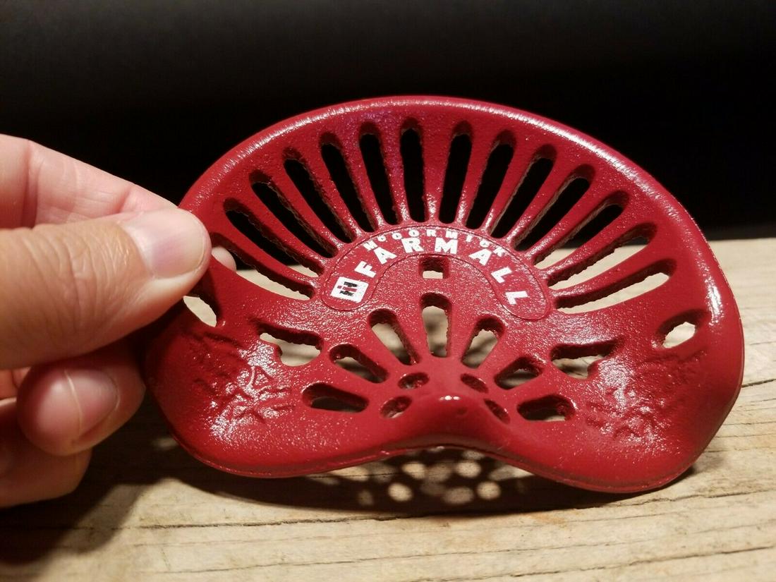 Cast Iron McCormick Farmall Miniature Tractor Seat: 4 3/4" wide x 4" Nice Reproduction antique solid cast iron McCormick Farmall tractor seat. Likely used as a salesman sample or a promotional paper weight. Certainly a great item! Be sure to see the im
