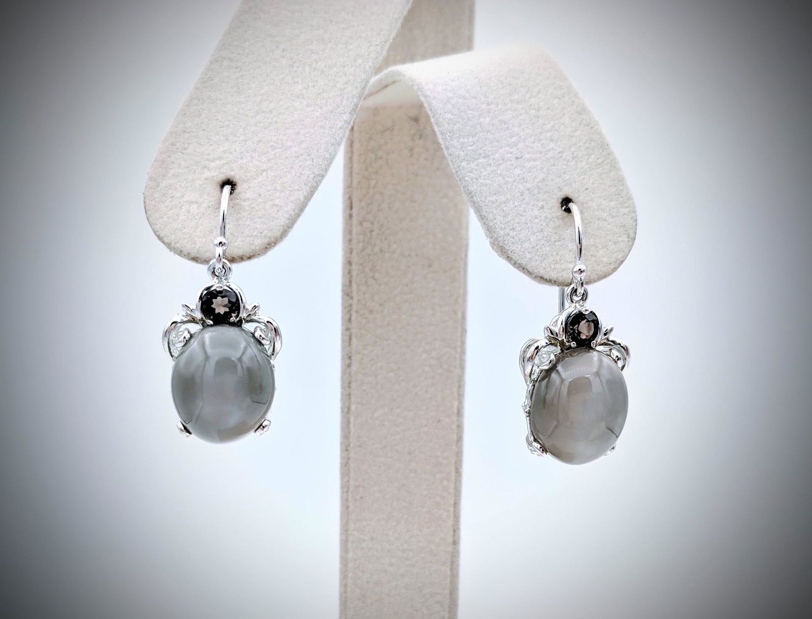 Sterling Silver Grey Moonstone & Smoky Quartz Earrings: Brand: Jean Lin Collection Title: Sterling Silver Grey Moonstone & Smoky Quartz Earrings Metal Purity: 925 Sterling Silver Gemstones: Grey Moonstone & Smoky Quartz Carat Weight: Each earring has 1 Ova