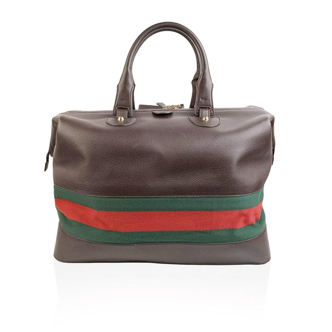 Gucci Brown Leather Travel Weekender Travel with: Brown leather travel bag by GUCCI with Web green and red stripes on the bottom. Upper zipper closure with padlock (keys and leather clochette is included). 5 Bottom gold metal feet. Beige internal lin