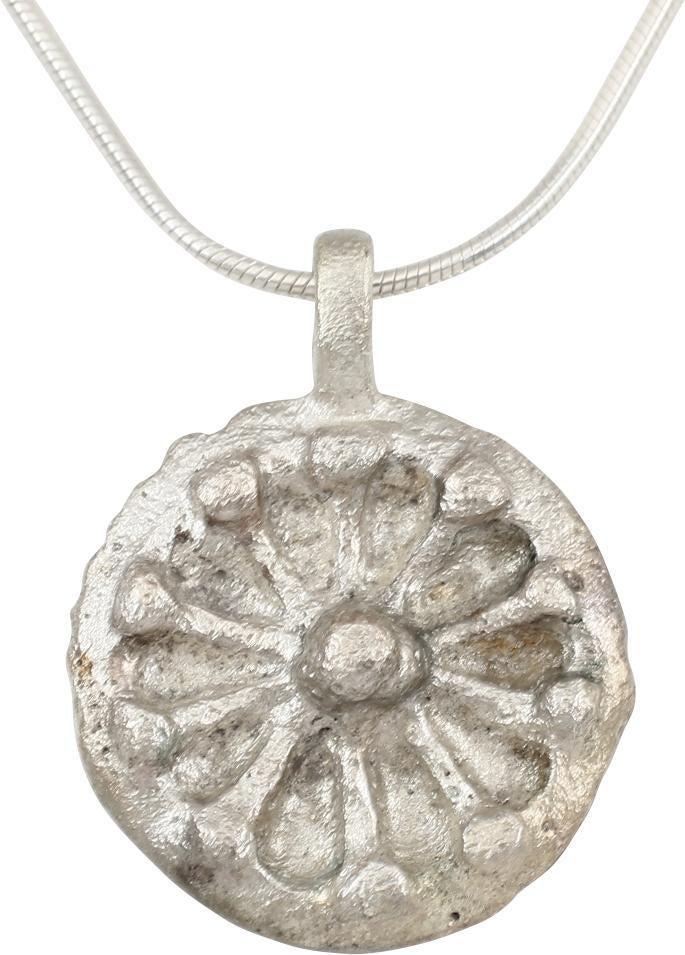 FINE ROMAN MYSTICAL PENDANT NECKLACE C.200-400 AD: Wheel form over 3/4” diameter. Modeled in high relief with a twelve spoke wheel. Each spoke terminal with a raised num and a larger nub at the center. The concept of the Rota Fortunae, the Wheel