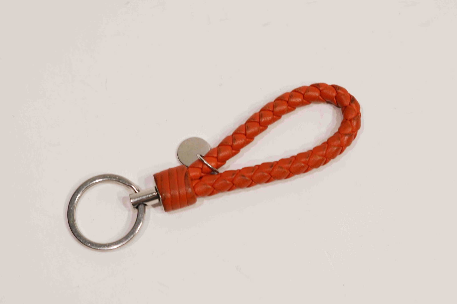 Bottega Veneta Orange Keychain: Title: Bottega Veneta keychain Orange Brand: Bottega Veneta Date: N/A Materials: Leather Measurement: N/A Additional Information: Bottega Veneta Woven Key chain. An engraved logo detail adorns this mo
