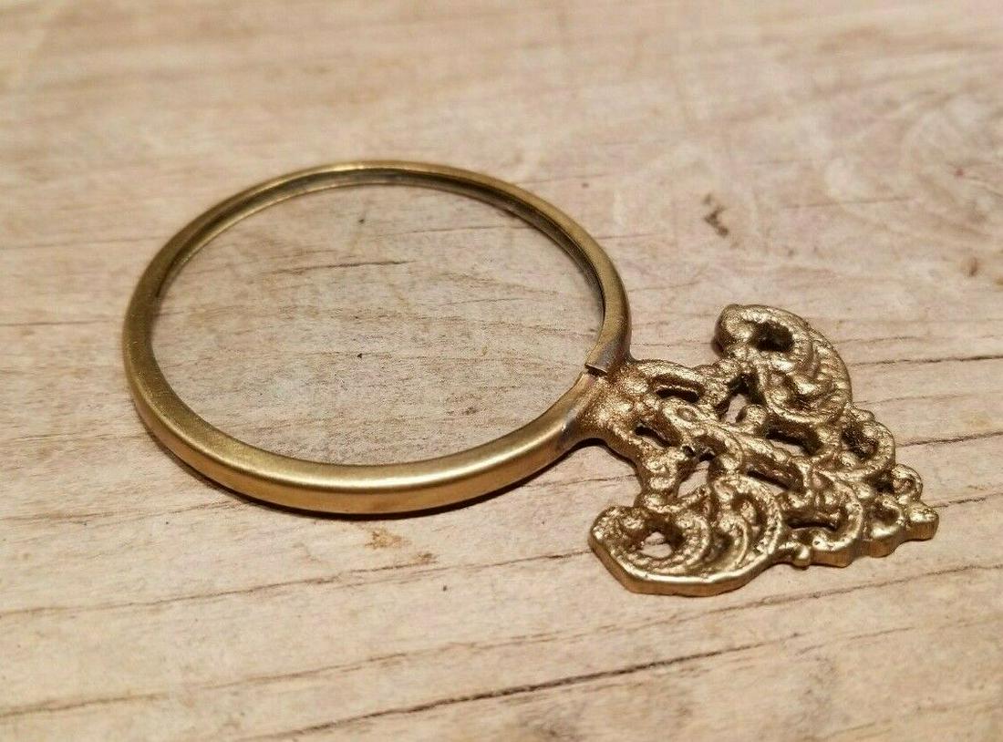 Small Brass Ornate Magnifying Glass Lens: 2 3/4" Long x 1 5/8" Wide Wonderful reproduction vintage brass magnifying glass. Nice heavy quality piece all solid brass unsure of the magnification strength, but it does magnify... Makes the perfect