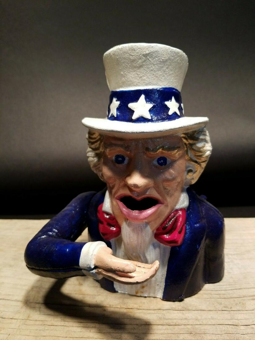 Uncle Sam Mechanical Coin Bank: 6" Wide x 7 1/2" tall Great reproduction folk art cast iron Uncle Sam Mechanical Coin Bank. This piece was made to look just like an antique, but is actually a reproduction. Like the antiques you pres