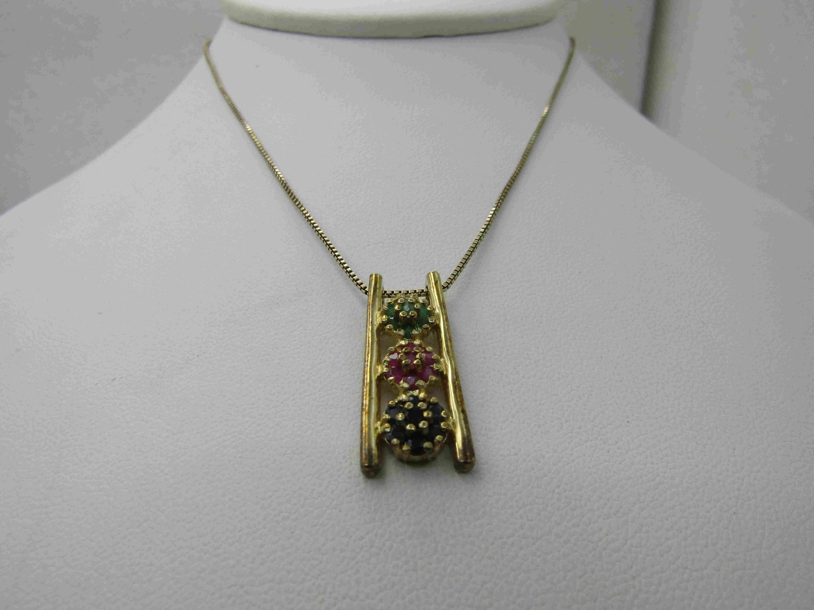 Sterling Vermeil Emerald, Ruby, Spinel Necklace, 18",: Sterling Vermeil Emerald, Ruby, Spinel Necklace, 18", Signed R. Ladder style pendant with a blossom w ith emeralds, rubies and blue spinels between the vertical supports. It is appx. 1" long and taper