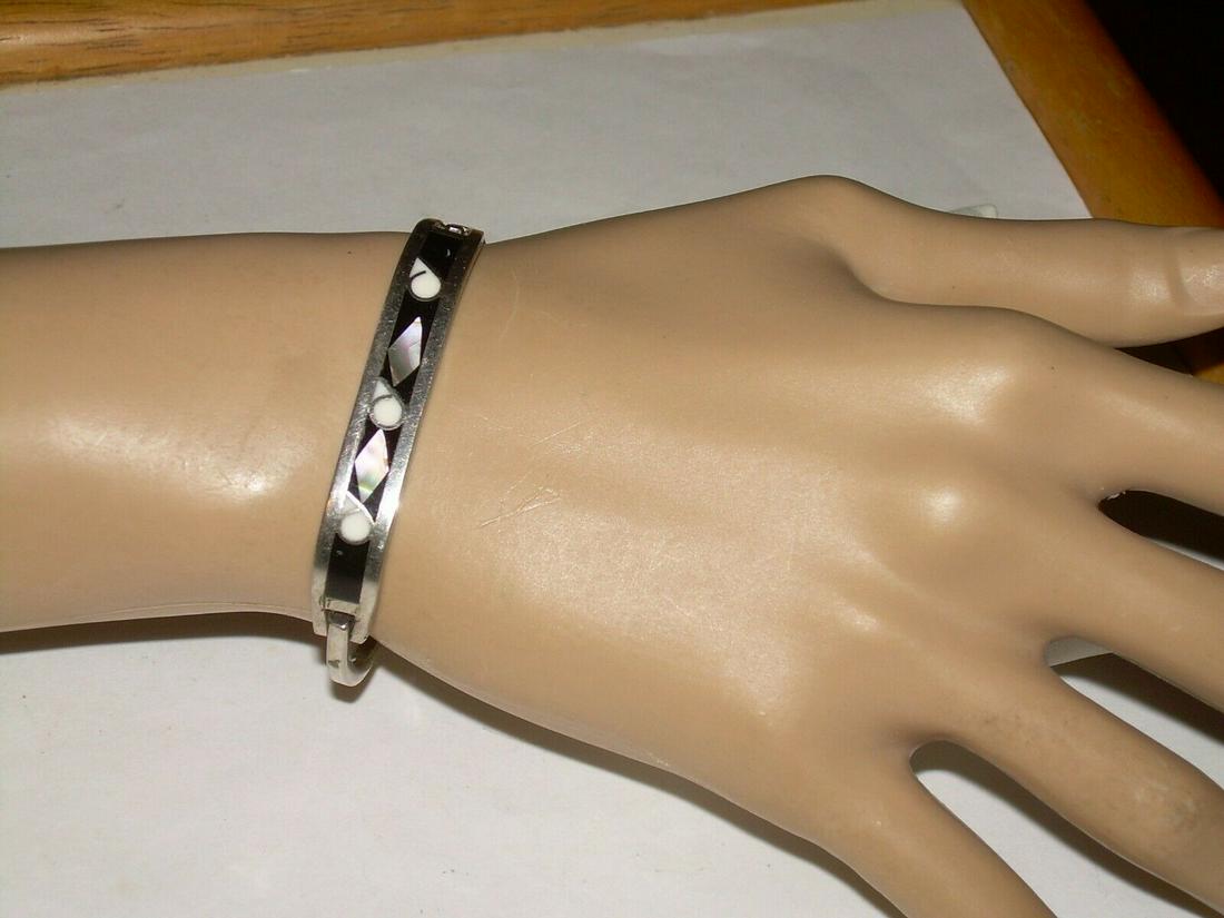 Vintage silver inlaid black enamel bracelet. The inlay: Vintage silver inlaid black enamel bracelet. The inlay has Abalone and Mother Of Pearl accents. The bracelet measures 2 1/4" wide and 2" from the front to the back. The opening is 2". The bracelet is
