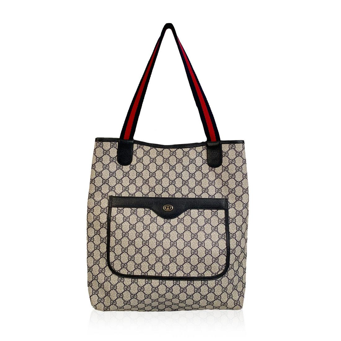 Gucci Vintage Blue GG Monogram Canvas Shopping Bag Tote: Beautiful Gucci tote made in monogram canvas with navy blue leather trim. Blue/Red/Blue striped canvas shoulder straps. 1 front patch pocket. Enameled GG- GUCCI logo tab on the front. Blue canvas lini