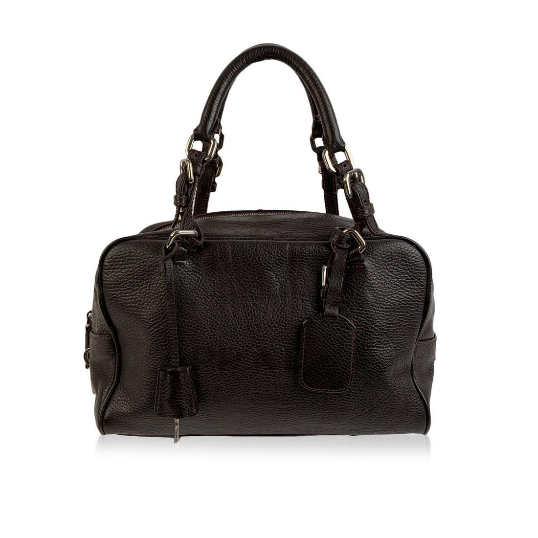 Prada Dark Brown Leather Logo Satchel Boston Bag: Prada brown leather boston bag. Crafted in soft brown pebbled leather. Silver metal hardware. Prada logo embossed on the front. Upper zipper closure. Side Prada padlock with keys and leather clochette