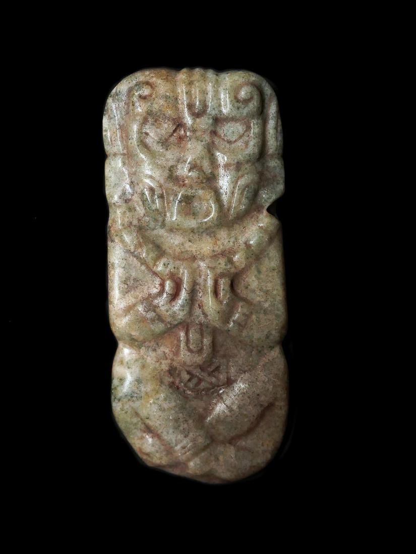 Mayan Jade Pendant: Title: Mayan Jade Pendant Description: Sculpted pectoral plaque representing a standing dignitary, richly adorned. The arms are folded and resting on the chest. With both of hands, he is holding a cer