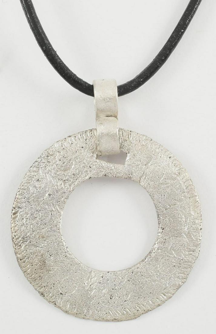 VIKING PROTECTIVE BROOCH NECKLACE 10th C. AD: Silvered bronze, over 1 1/8” diameter. Broad stipple edged ring with a repeated circular motif, now partially obscured from burial. Professionally refurbished with the silver overlay restored, o