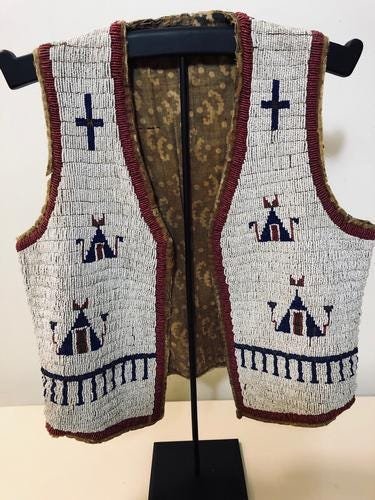 CHILD’S BEADED INDIAN VEST: Title: CHILD’S BEADED INDIAN VEST Provenance/additional info: 14" WIDE X 16" LONG - ORIGINAL LINING - HAND SEWN - CIRCA 1900. Sold with stand Shipping: Domestic: Flat-rate of $55.00 to anywhere with