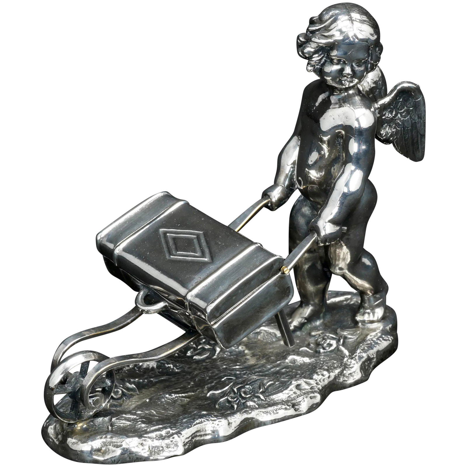 Victorian Cherub with Cart Silverplate Match Holder: Title: Victorian Cherub with Cart Silverplate Match Holder Size: 4 ¾Â” (12.1 cm) long x 4 ½Â” (11.4 cm) tall x 2 ¼Â” (5.7 cm) wide. Description: A heavy, shiny and deeply cast figure of a