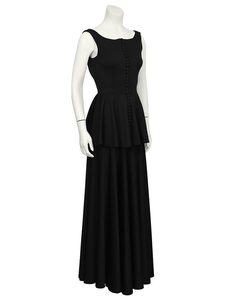 Jean Varon Black Jersey Gown With Peplum: Gorgeous black jersey gown with peplum by English designer Jean Varon from the 1960's. The gown has a boat style neckline and does up the front with multiple fabric covered buttons. Dramatic cowl in t