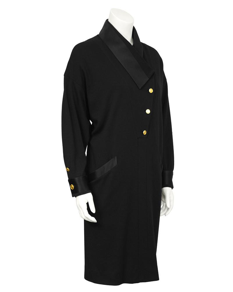 Chanel Black Wool Jersey & Satin Dinner Dress: Unique 1980's style dress features an asymmetrical collar finished with gold buttons stamped with “Coco Chanel France” surrounding Coco’s profile. The dress features diagonal pockets on the fron