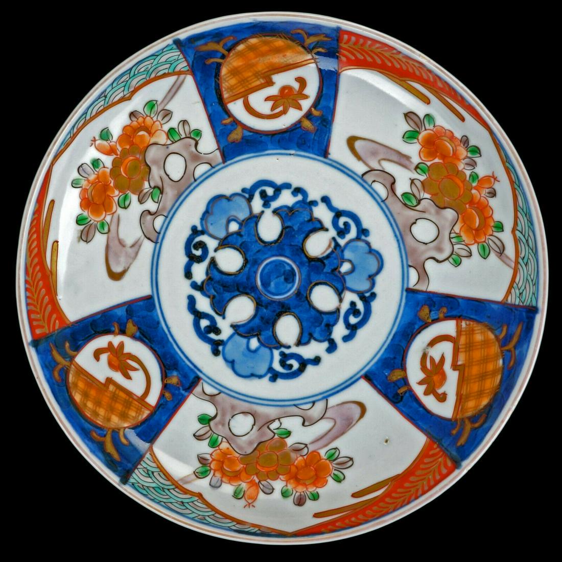 Japanese porcelain colored Imari plate early 20th C: Colorful, hand potted, hand painted, intricate Japanese porcelain dish with floral arrangements and Japanese fabric designs. A round heavy porcelain plate with alternating panels of rocks and flowers 
