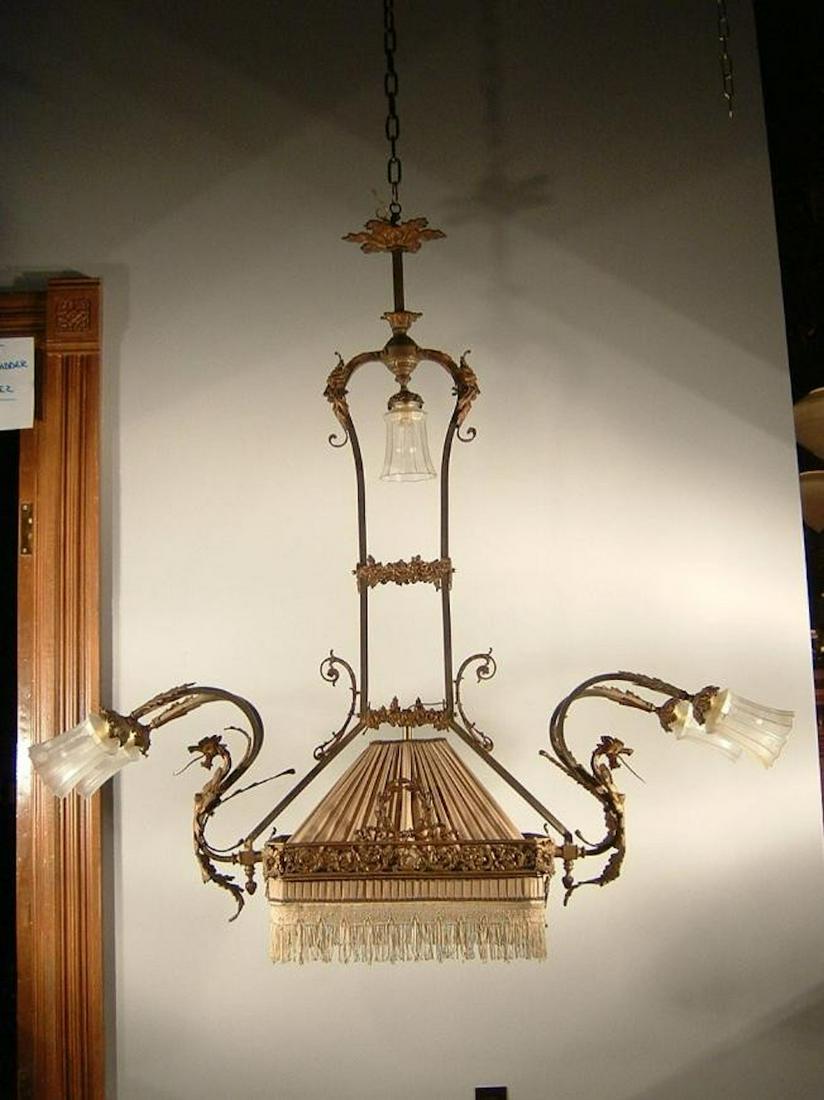 French Pool Table Light Fixture: Ca. 1890 A lighting fixture that defies description, this French made billiard table lamp is trimmed with a superb array of odd faces and mythical creatures. Unrestored golden finish with a rebuilt cl