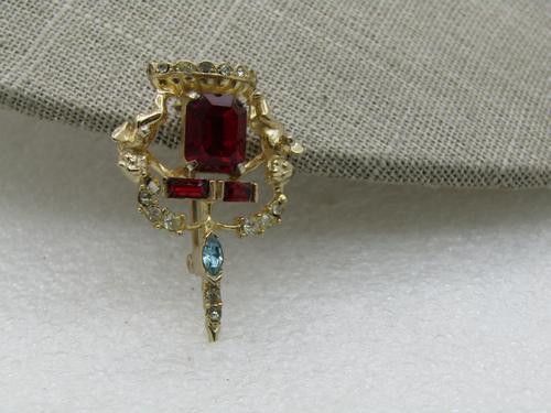 Vintage Rhinestone Cherub Crown Brooch, 1960's: Vintage Rhinestone Cherub Crown Brooch, 1960's, Gold Tone. 1.5" tall and 1" wide. Large red princess cut rectangular stone and two baguettes, with clear stones and a blue marquise stone. There is a ch