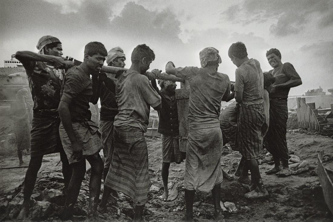 SEBASTIAO SALGADO - Transport of a Heavy Piece, 1989: Artist: Sebastiao Salgado Title: Transport of a Heavy Piece at the Ship Breakers Work Site, Bangladesh, 1989 Medium: Photo Litho, 1999, Italy Dimensions: 9.6x6.4" Description: Heat Wax Mounted on 8.5x
