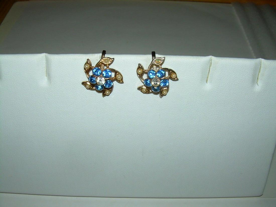 Rhinestone & Pearl Screwback Earrings With Goldtone In: Vintage screwback earrings formed in a shape of a pin wheel. The outside leaves are gold tone with a faux pearl in the center of each one. The center is raised and has 5 blue rhinestones forming a blo