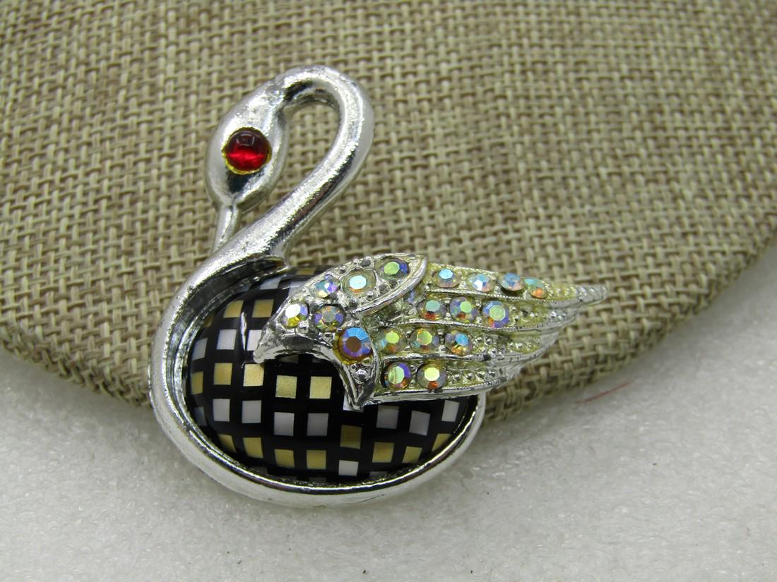 Vintage Rhinestone Swan Brooch, Inlaid Body, 2" Tall: Vintage Rhinestone Swan Brooch, Inlaid Body, 2" Tall and 1.7/8" wide. Silver tone body with raised wing that has aurora blorealis rhinestone in the wing and a red cabochon eye. The blody has a black b