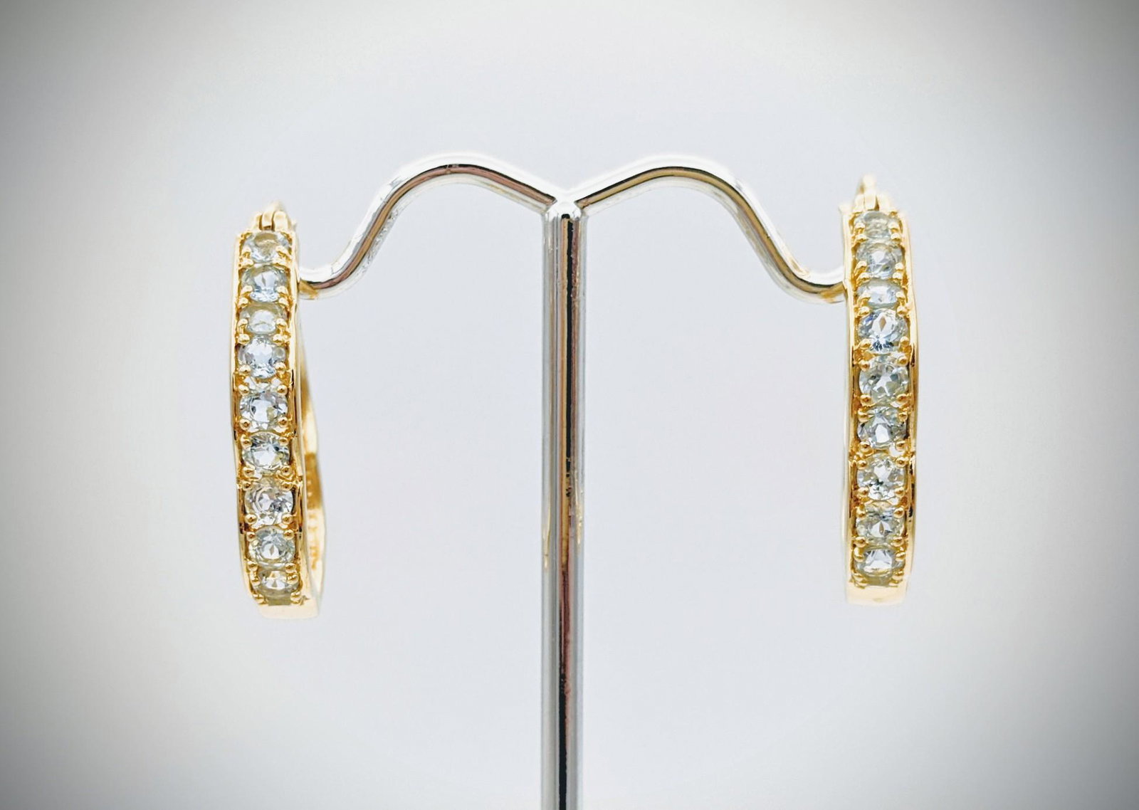 Sky Blue Topaz Hoop Earrings: Brand: Jean Lin Collection Title: Sky Blue Topaz Hoop Earrings Metal Purity: Gold Plated 925 Sterling Silver Gemstones: Sky Blue Topaz Carat Weights: Each Earring has 10 Round Blue Topaz at 3mm (0.11c