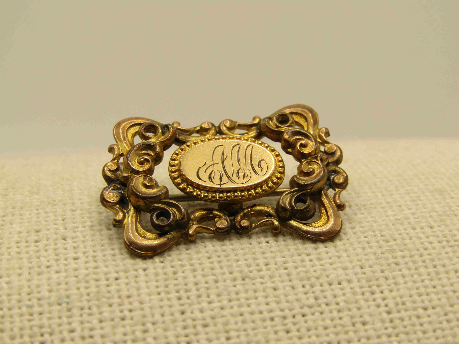 Victorian 10KT G.F. Engraved AM Filigree Scrolled: Victorian Engraved AM Filigree Scrolled Brooch, 10kt G.F. C-Clasp, 1" by 3/4" tall. Tiered scrolls on the sides and single scrolled layer above and below the center raised oval that is engraved AM in 