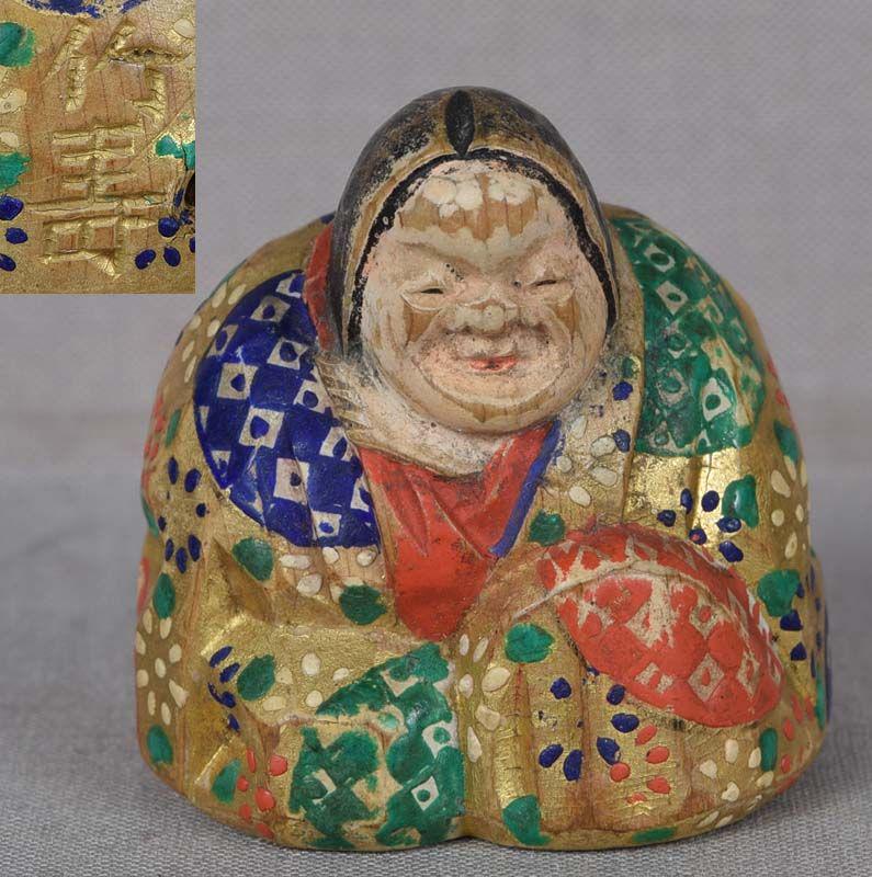 19c shunga Hida saishiki netsuke OKAME by CHIKUJU: 19th century wooden shunga netsuke representing seated Okame wearing richly patterned robe and smiling widely as she touches herself as shown on the bottom of the netsuke. The netsuke is skillfully ca