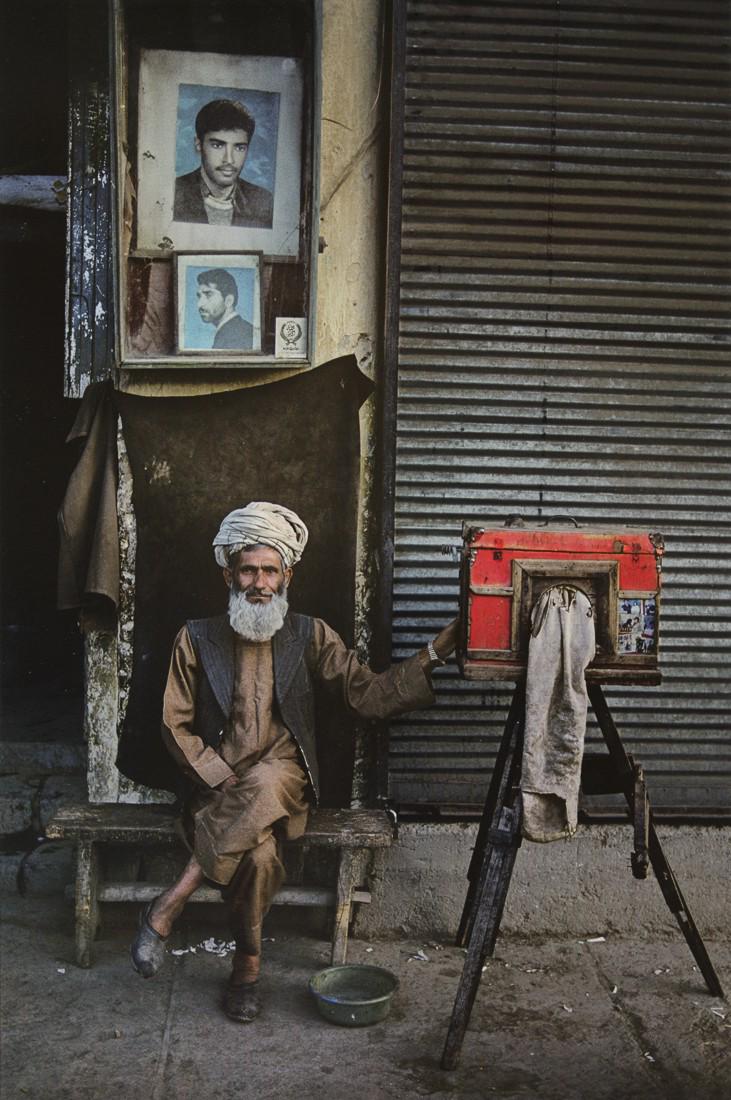 STEVE MCCURRY - Portrait Photographer, Kabul, 1992: Artist: Steve McCurry Title: Portrait Photographer, Kabul, Afghanistan, 1992 Medium: Photo Litho, 2012, Italy Dimensions: 9.25x13.95" Description: Heat Wax Mounted on 14x18" Conservation Board Artist