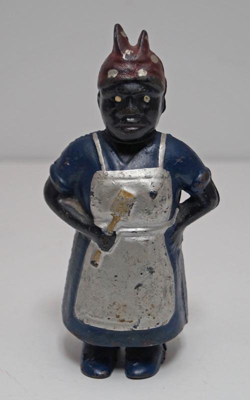 Antique Mammy w/ Spoon Cast Iron Still Bank: Title: Antique Mammy w/ Spoon Cast Iron Still Bank Date/Period: Circa 1905-1930's. Dimension: 5 7/8" tall x 2 7/8" wide. Additional Information: Mammy holding Spoon dressed in blue with silver. . apro