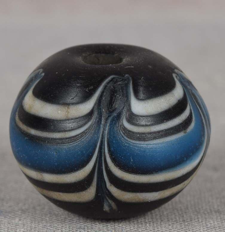 19c glass OJIME netsuke slide: 19th century glass ojime (slide bead for tightening the cord going from netsuke to inro) in slightly flattened ball shape with black body and leaf and white and blue wave design. Beautiful surface, ve
