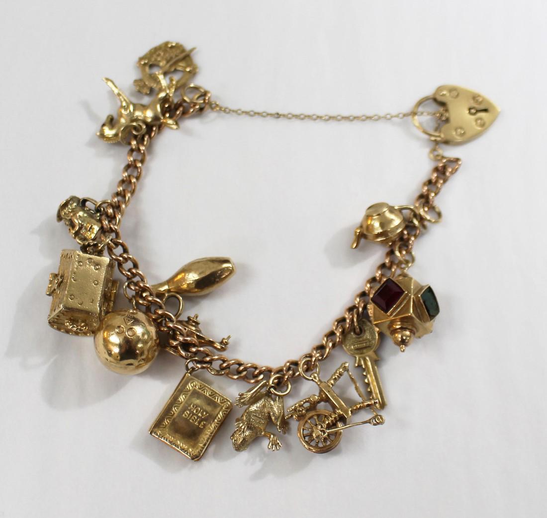 9ct Gold Vintage Charm Bracelet with 14 Charms: 9ct Gold Vintage Charm Bracelet with 14 Charms English. 20th century. Bracelet with 14 charms; padlock, teapot, lantern, key, spinning wheel, frog, genie lamp, bible, ball, skittle, treasure chest, ch