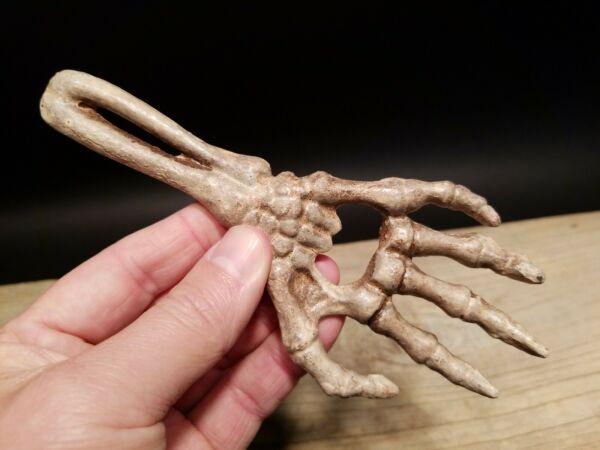Cast Iron Bone Hand Beer Bottle Opener: 6 5/8" Long x 2 7/8" Wide Great reproduction cast iron bottle opener. This piece was made to look just like an antique, but is new. As you see in the images it is in the form of a skeleton hand. Great