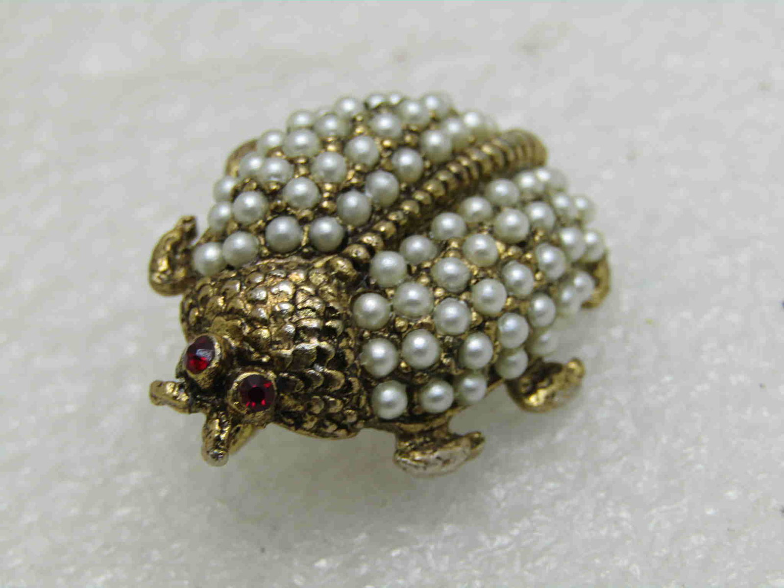 Vintage Egyptian Theme Seed Pearl Beetle Brooch: Vintage Egyptian Theme Seed Pearl Beetle Brooch. Red rhinestone eyes. Circa 1950's-1960's. 68 seed pearls, 34 on each wing, no pearls missing. Gold tone. Appx 1.3" long, 1" wide. Very good vintage con
