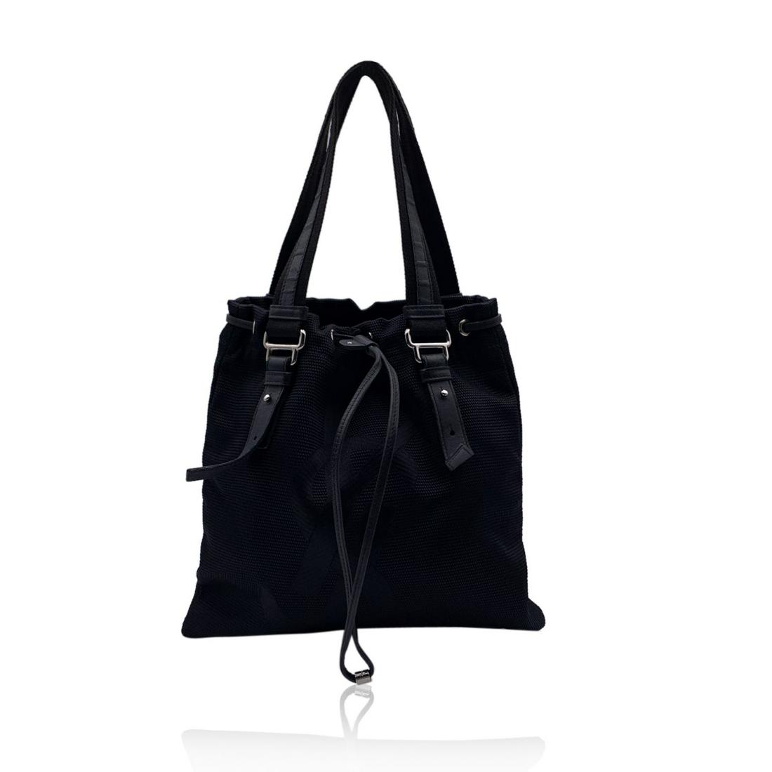 Yves Saint Laurent Black Canvas Logo Kahala Tote: YVES SAINT LAURENT Black canvas 'Kahala Sac' tote bag with jacquard YSL logo on the front. Drawstring closure on top. Double canvas and leather handles. Black satin lining. 1 side zip pocket inside. '