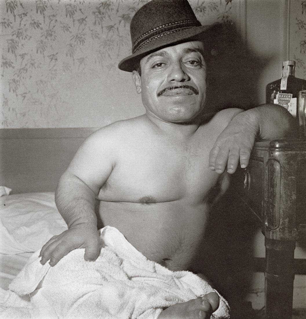 DIANE ARBUS - Mexican Dwarf in his Hotel Room in NYC: Artist: Diane Arbus Title: Mexican Dwarf in his Hotel Room in NYC, 1970 Medium: Photo Litho, 1972, USA Dimensions: 8.3x8.65" Description: Heat Wax Mounted on 11x14" Conservation Board Artist Bio: Dian
