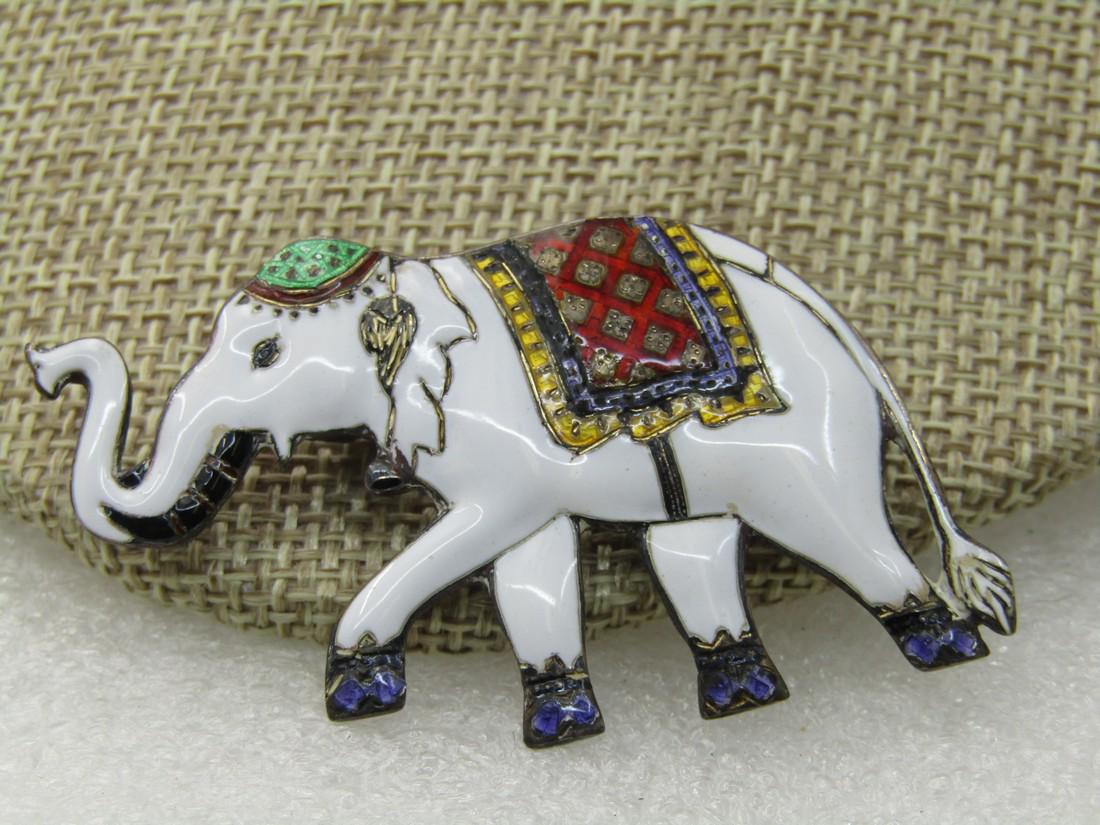 Vintage Sterling Siam White Enameled Elephant Brooch,: Vintage Sterling Siam White Enameled Elephant Brooch, 10.80 gr., 2" by 1.25". Enameled in white with a green cap, gold and red saddle blanket and purple hooves and black tusks. Signed Sterling and Sia