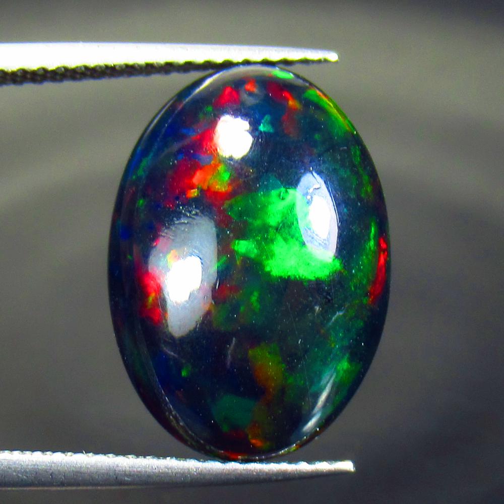 6.40 Ctw Natural Black Fire Opal Oval Cabochon: Title: 6.40 Ctw Natural Black Fire Opal Oval Cabochon Clarity: Opaque Gemstone: Natural Opal Carat Weight: 6.4 Dimensions: 17.40 x 12.40 x 6.30 mm Additional Information: Shape - Oval Cabochon / Color