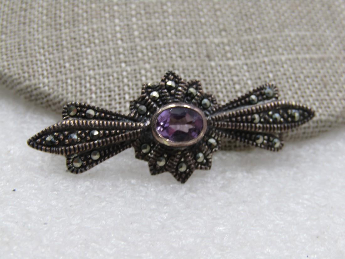 Vintage Sterling Amethyst Marcasite Brooch, Signed A: . 1.75" wide and 5/8" tall with a raised center oval amethyst that is appx. 8mm by 6.5mm with pointed accents and marcasites throughout the brooch. Marked sterling and tested, weight is appx. 4.99 gra